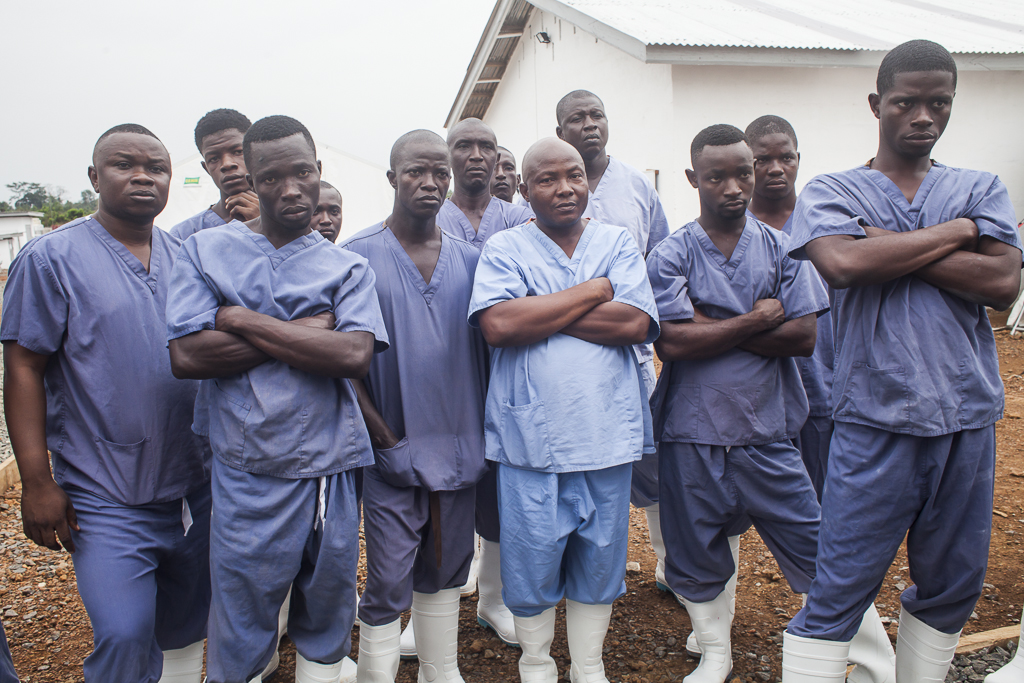 Part of the hygienist team managed by Solidarites International, in the picture they are attending a formal meeting. From left to right, Sulaiman, Haruna, Vandy, Ibrahim, Dauda, Festus, Mohamed, John, Patrick, Augustine, Umaru, and Ibrahim Bah. The hygienists are workers of the Ebola treatment center who face the most dangerous tasks in the high risk contagion areas; like the morgue, the triage and the wards and toilets of patients. They are in charge of the infection prevention control; it includes the disinfection, cleaning, ambulance arrival, admission of patients, dead body management and support to medical workers. Ebola Treatment Center. Moyamba. Sierra Leone.